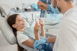 young girl in a dental chair smiling, undergoing a routine exam