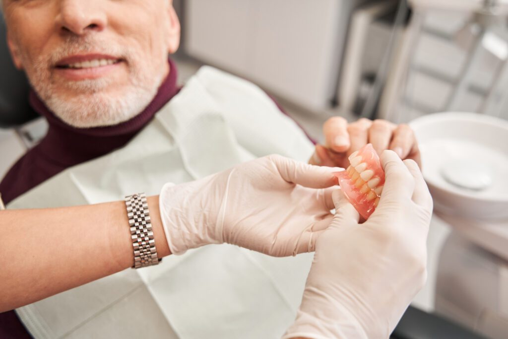 doctor showing a pair of dentures to a patient in Manhattan